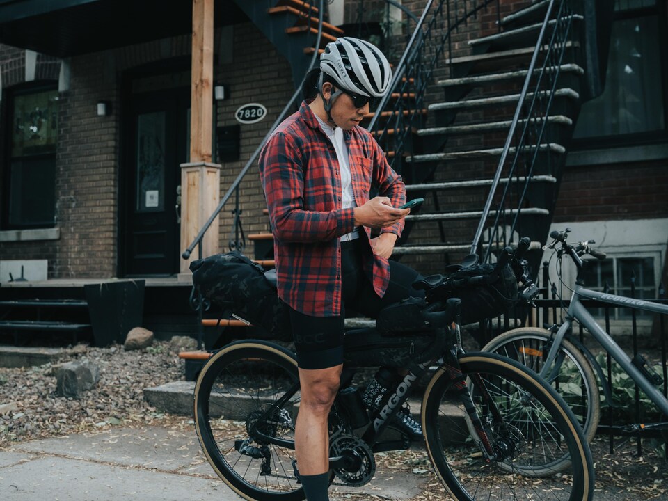 A man looks at his phone while sitting on his bicycle.