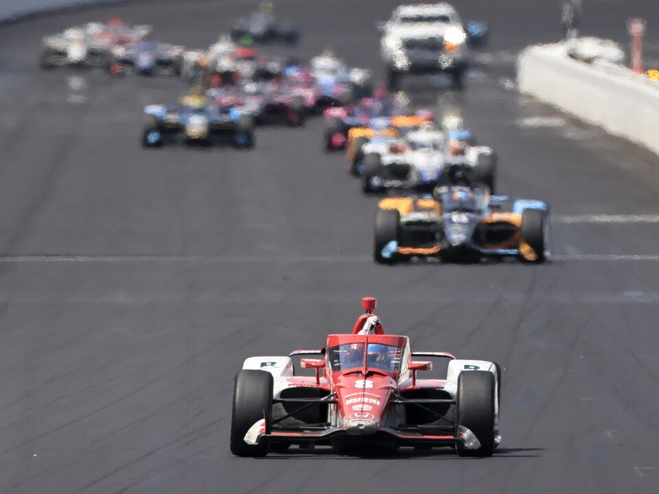 An Indycar-style race car, shot directly, was a few steps ahead of the peloton.