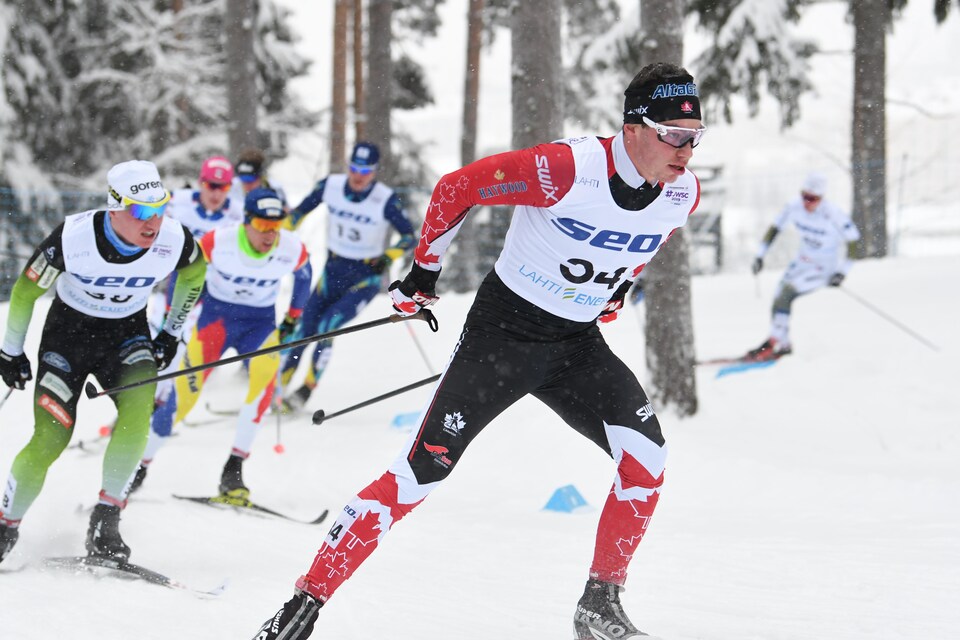 Le fondeur Antoine Cyr pousse dans une montée devant un groupe d'autres skieurs.