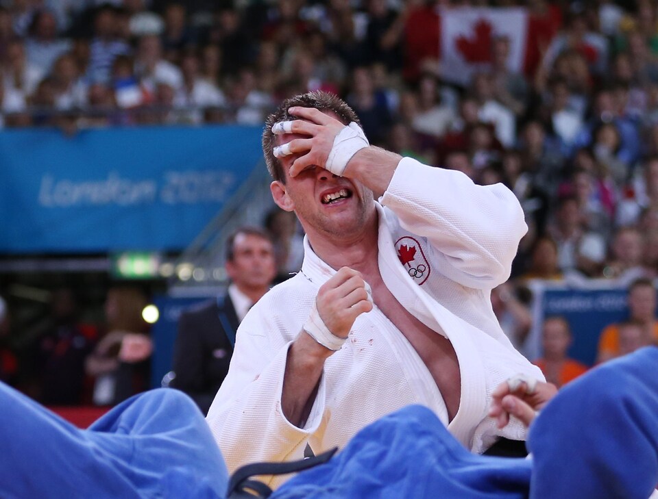 Le judoka canadien se cache le visage et fond en larmes.