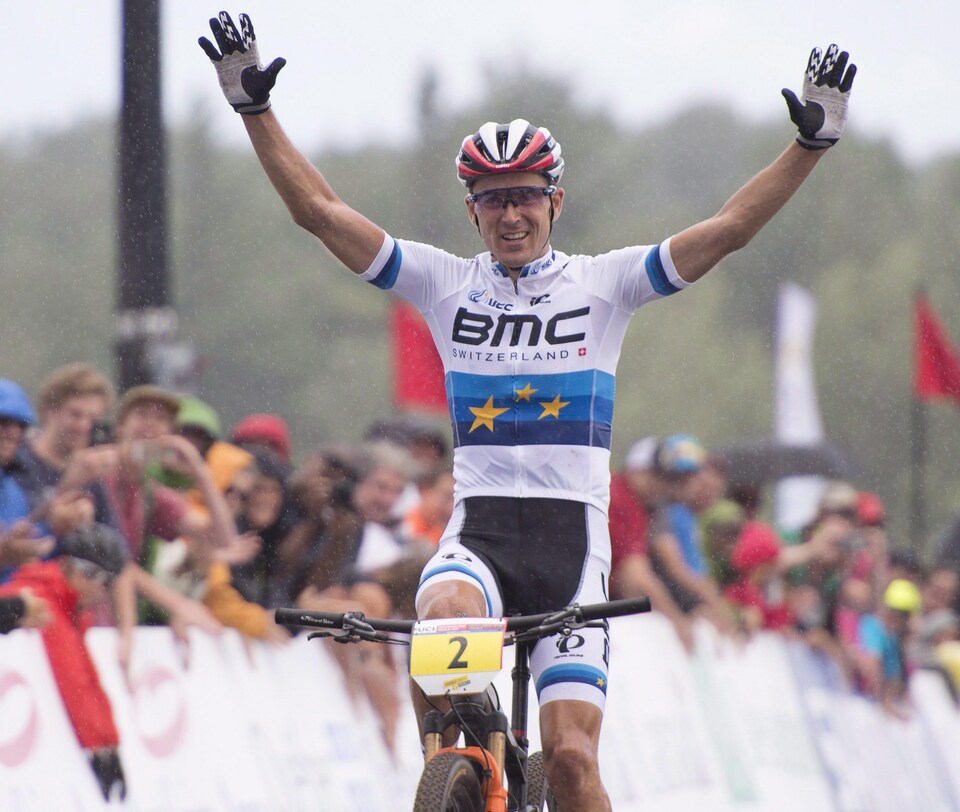 Le Français Julien Absalon lève les bras pour célébrer sa victoire à la Coupe du monde de vélo de montagne de mont Sainte-Anne, en 2016.