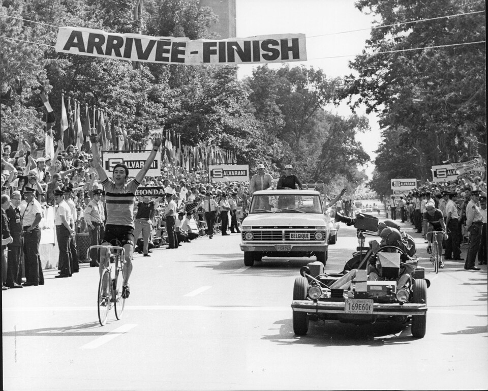 Le Belge Eddy Merckx lève les bras en traversant le fil d'arrivée de l'épreuve sur route des Championnats du monde de cyclisme. À droite, derrière l'auto-caméra, le Français Raymond Poulidor se contente de la 2e place.