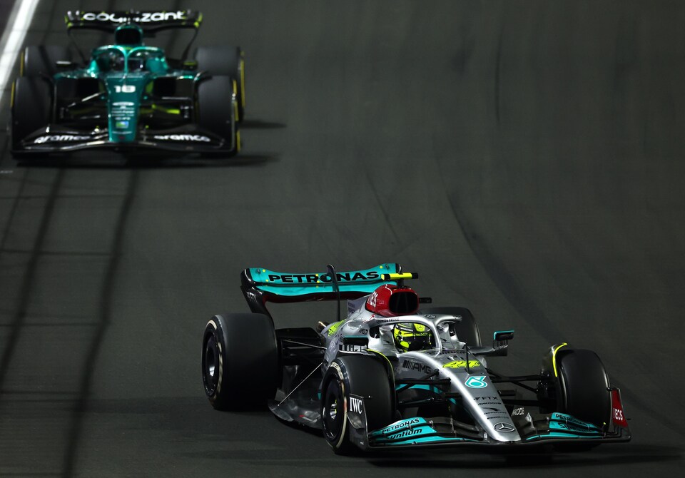 Deux monoplaces F1 se suivent de près sur un circuit éclairé.