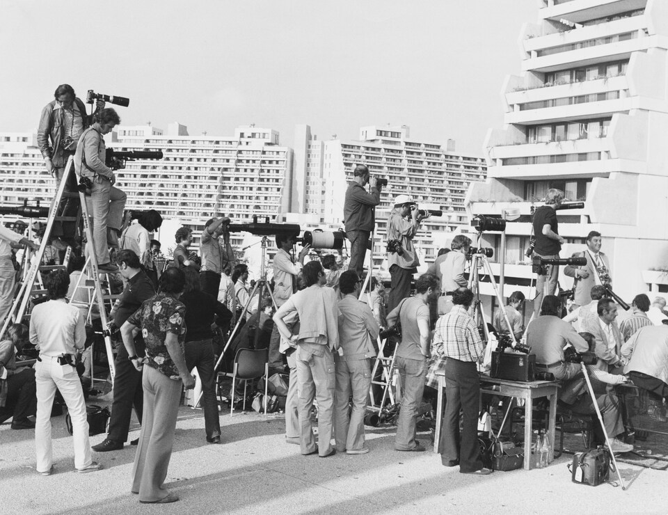 Journalists with cameras and cameras crowded in front of the houses, others perched on the stairs.