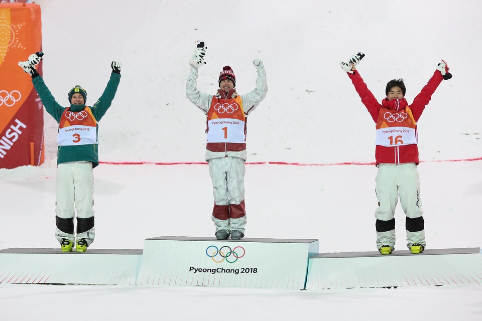 Le Canadien Mikaël Kingsbury célèbre sa victoire à l'épreuve des bosses en compagnie des médaillés d'argent et de bronze.