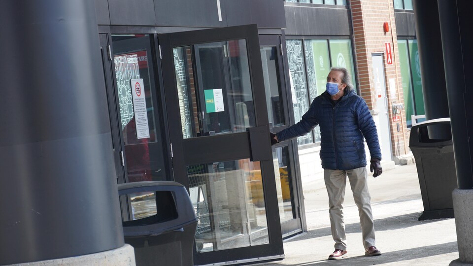 Un homme portant un masque tente d'ouvrir une porte.