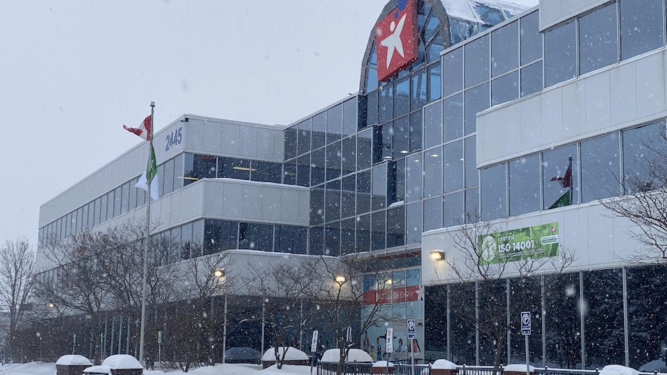 Building with the school board logo on the glass wall, during a mild snow shower.