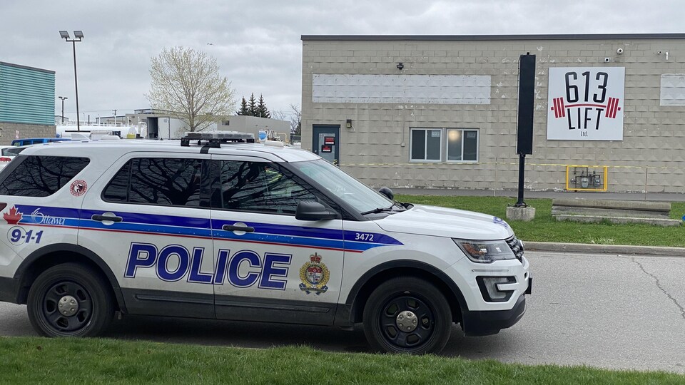 Une voiture de la police d'Ottawa devant un édifice.