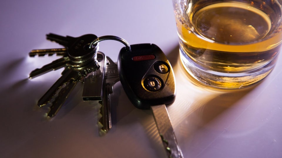 Des clés se trouvent à côté d'un verre d'alcool. 