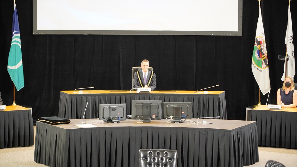 Le nouveau maire d'Ottawa, Mark Sutcliffe, assis au centre de la salle du conseil municipal.