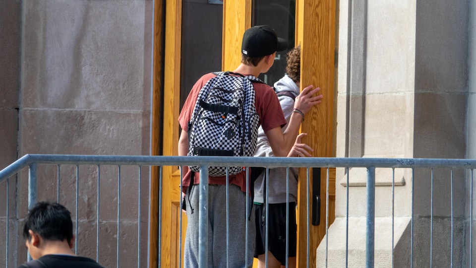 Des élèves entrent dans un bâtiment avec leur sac sur le dos.