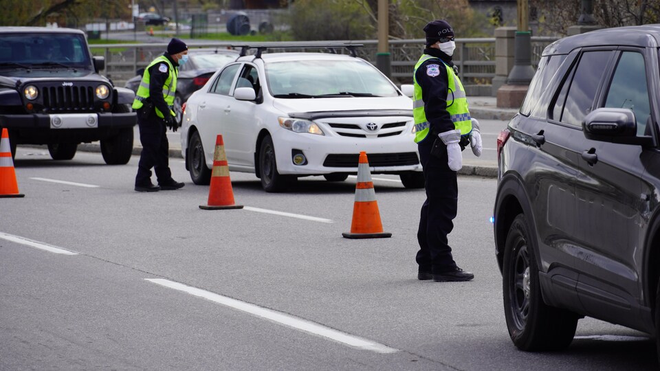 Des policiers s'adressent à des automobilistes dans une file de voitures.