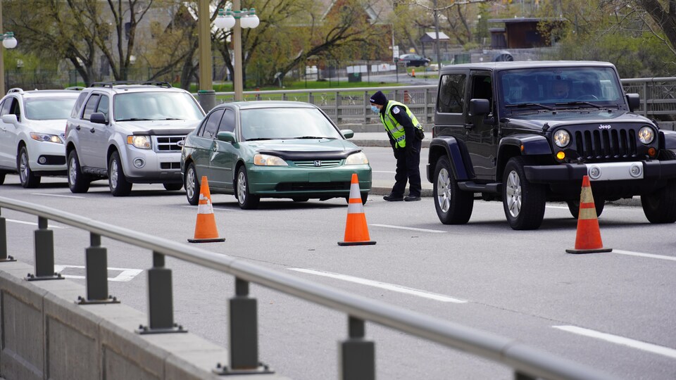 Un policier s'adresse à un automobiliste, dans une file de voitures.