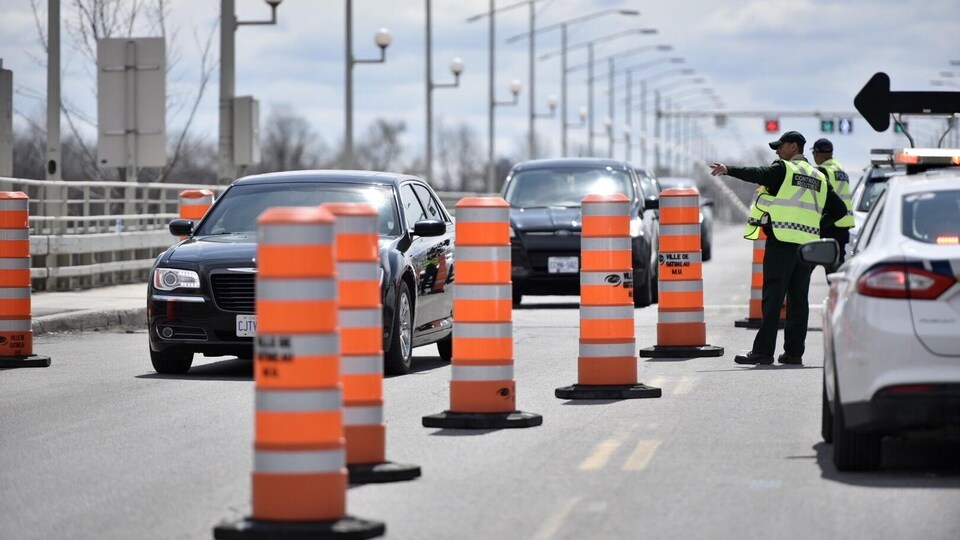 Un policier fait un signal à une voiture qui approche d'un contrôle routier.