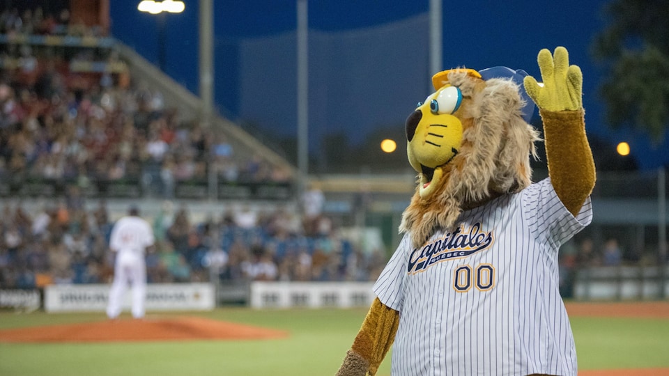Une mascotte des Capitales de Québec dans un stade qui salue la foule.