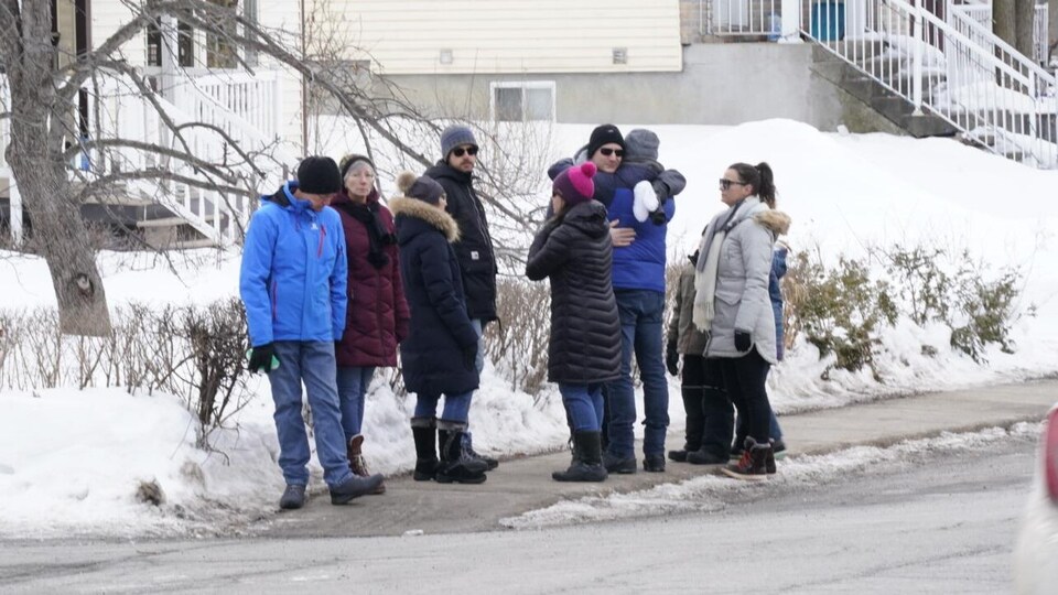Une dizaine de personnes attendant au coin d'une rue.