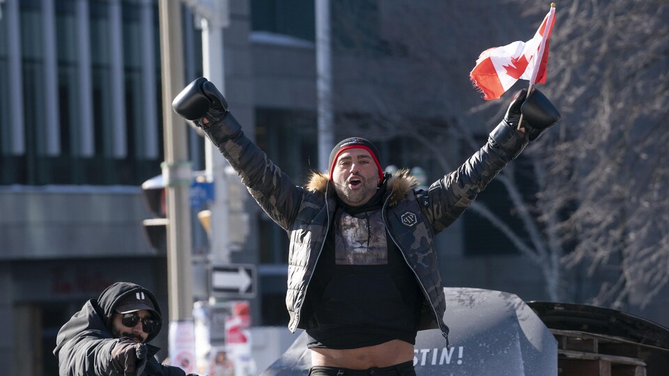 Un manifestant brandit un drapeau du Canada.