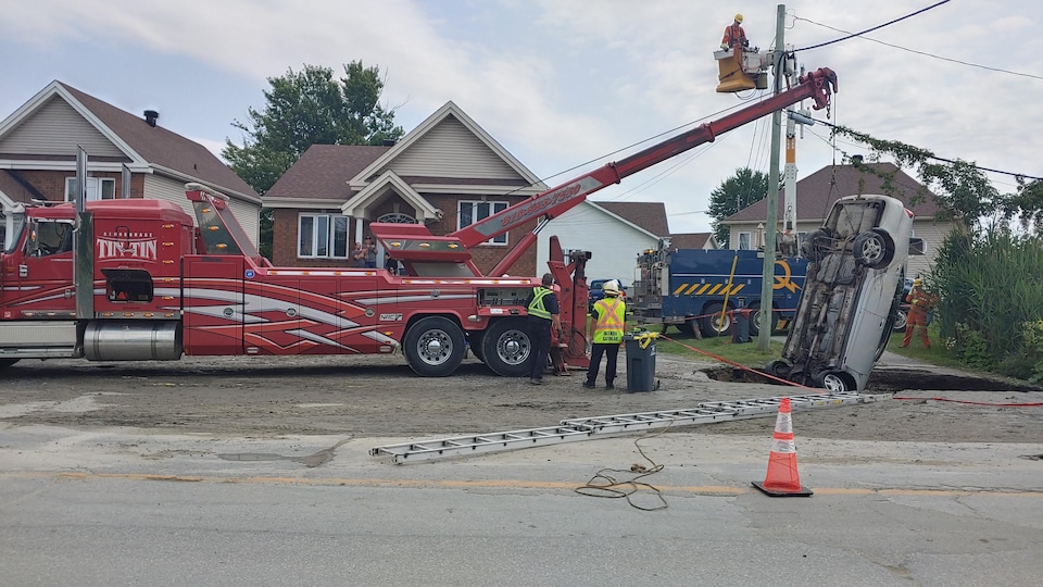 Un camion sort une voiture d'un trou dans la rue.