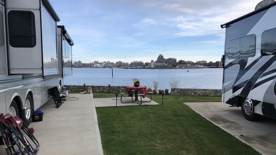 Un campeur a décoré une table d'une nappe et d'un pot de fleur à proximité de son véhicule récréatif garé au bord de l'eau, dans le port de Victoria.