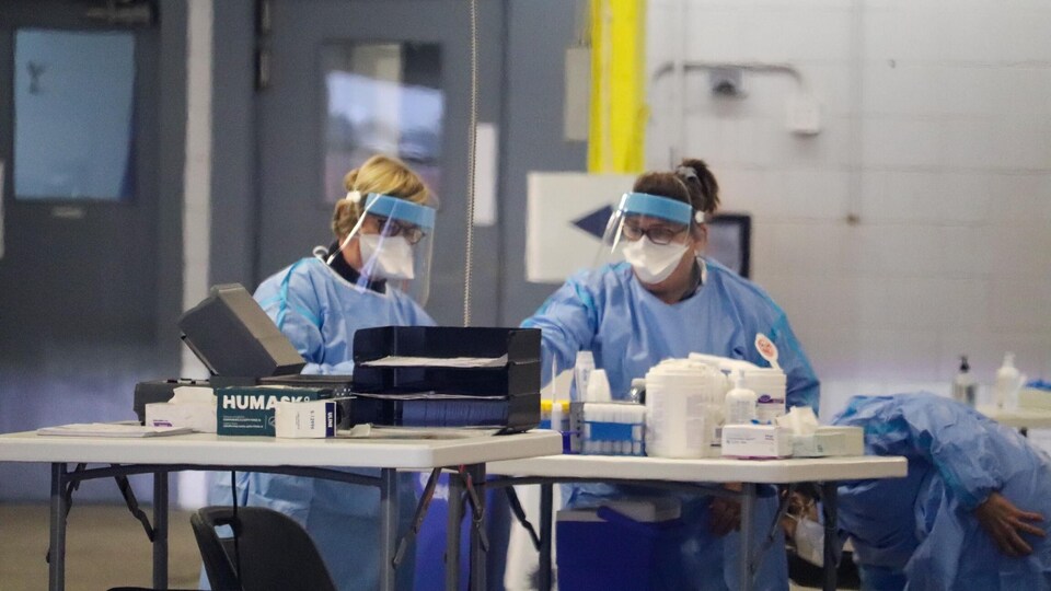 Deux personnes avec des équipements de protection dans un centre de dépistage à Québec.