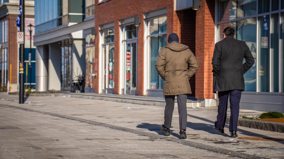 Deux personnes, de dos, marchent au centre-ville de Gatineau.