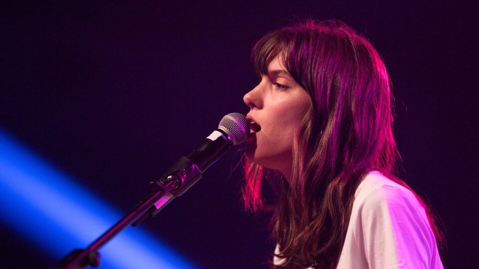 Une femme sur scène chante dans un micro.