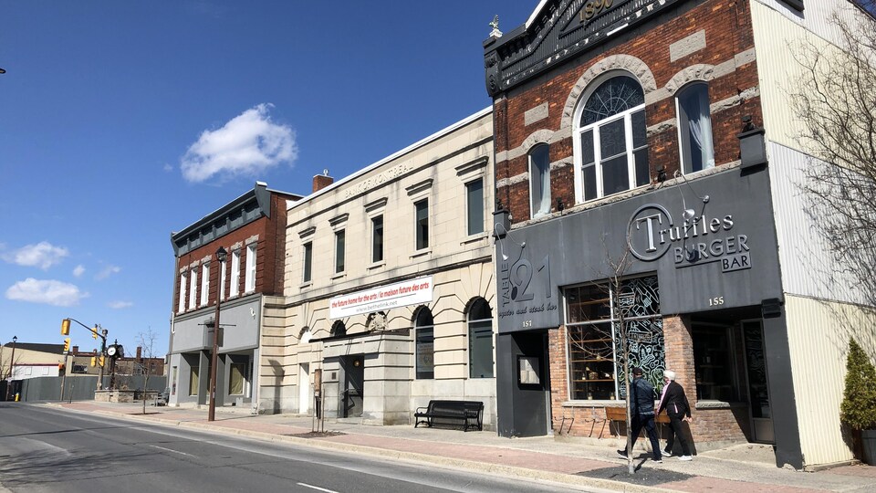 Deux piétons marchent sur le trottoir désert devant des boutiques fermées à Cornwall.