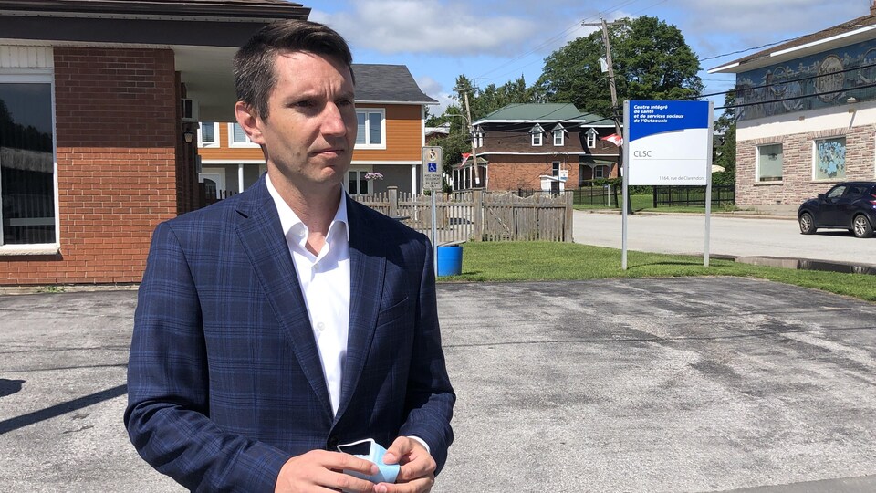 André Fortin, debout, regardant le journaliste de Radio-Canada.