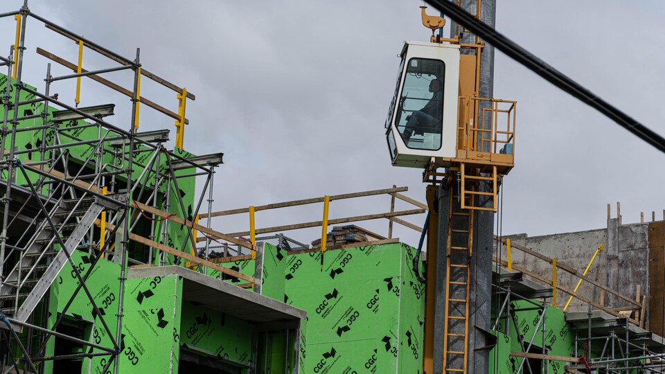 Un travailleur de construction dans l'habitacle de contrôle d'une grue.