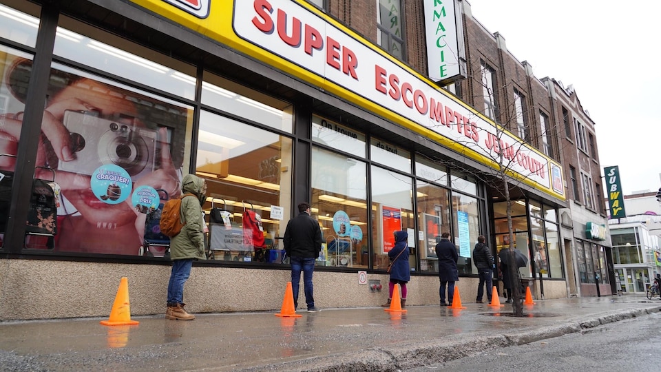 Des gens font la file devant une pharmacie sur l'avenue du Mont-Royal, à Montréal.