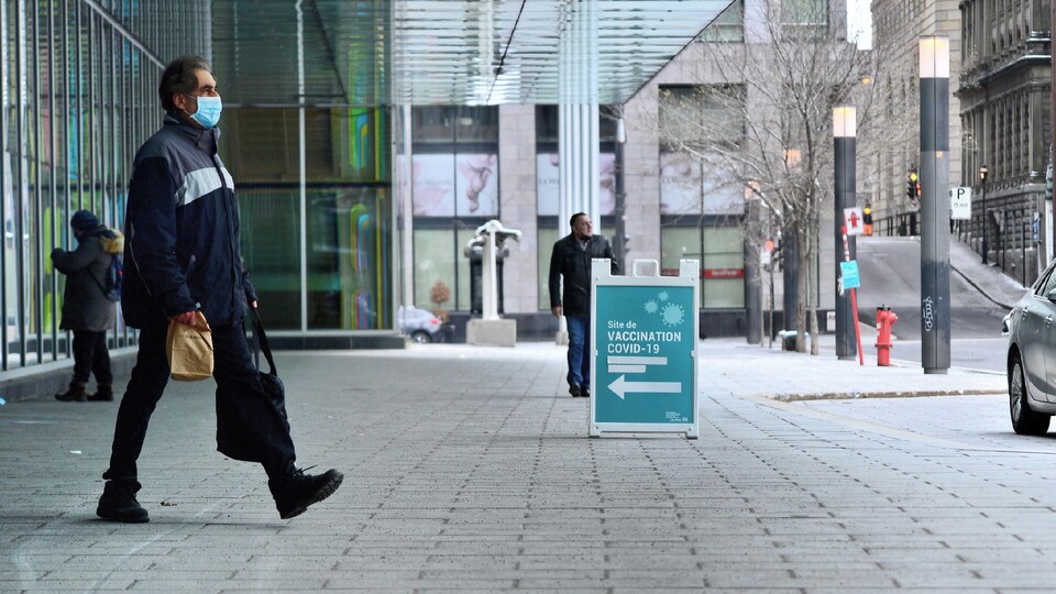 Un homme marche masqué dans la rue.