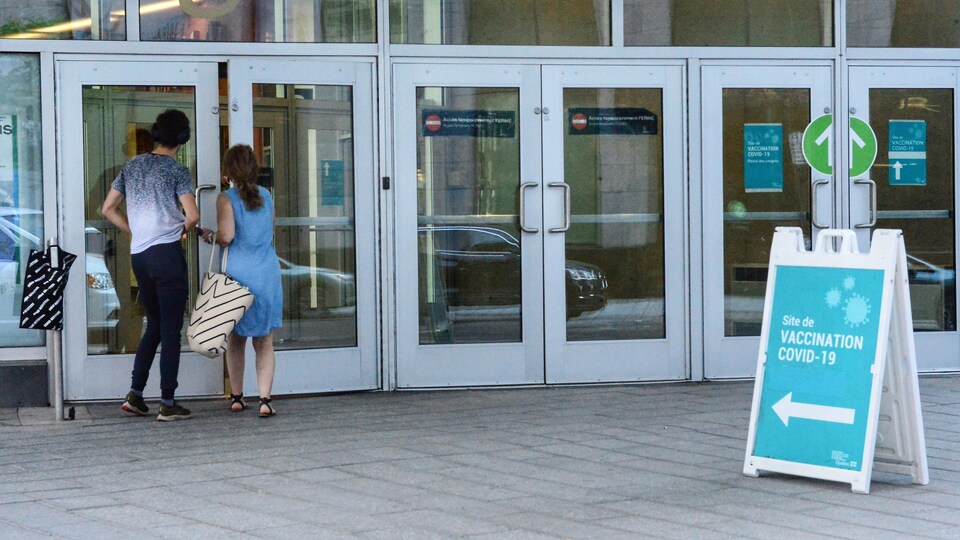 Deux personnes entrent dans une clinique de vaccination.