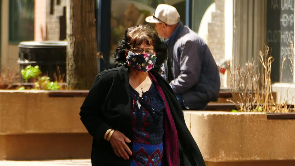 Une femme marche dans les rues de Regina en portant un masque.