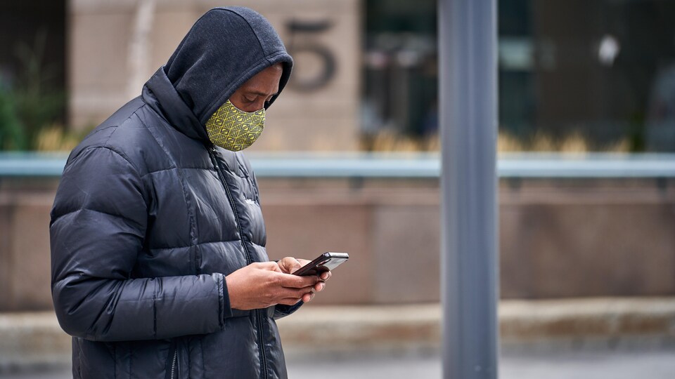 Un homme consulte son téléphone cellulaire.