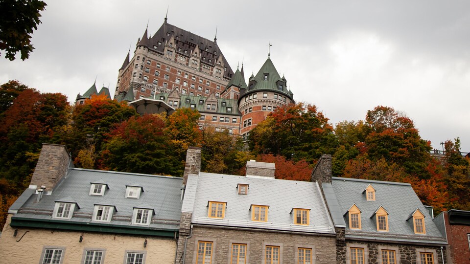 Le Château Frontenac surplombe des arbres aux couleurs d'automne ainsi que des bâtiments anciens.