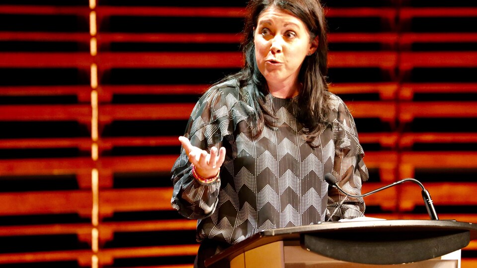 Marie-Josée Savard, derrière un lutrin, prend la parole lors du débat.