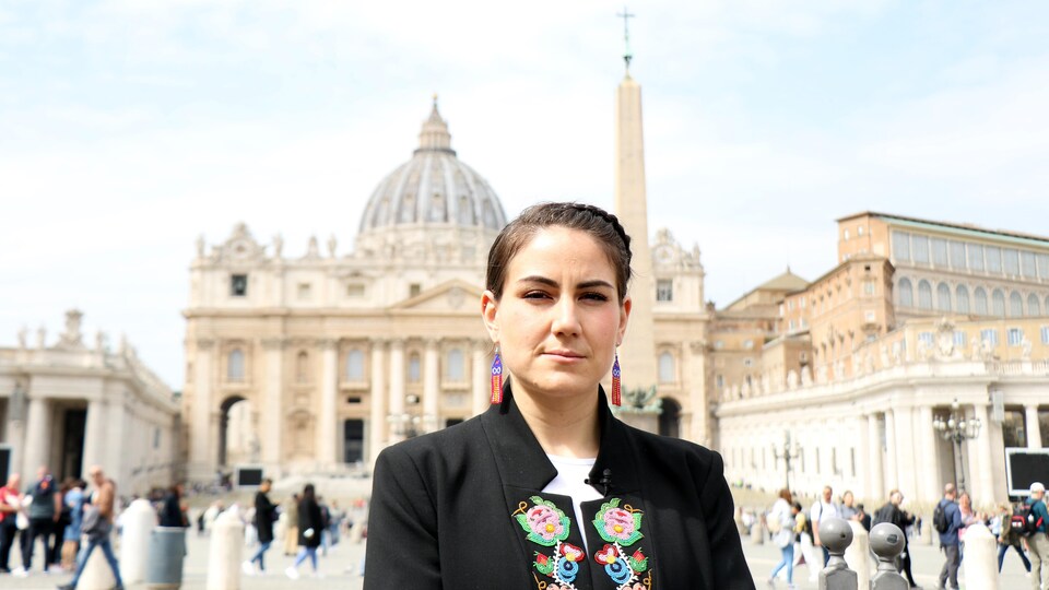 Une femme se tient debout sur la place Saint-Pierre au Vatican.