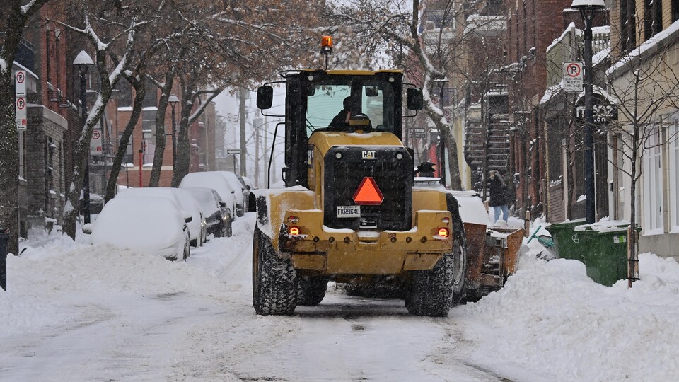 Un tracteur dans une rue enneigée. 