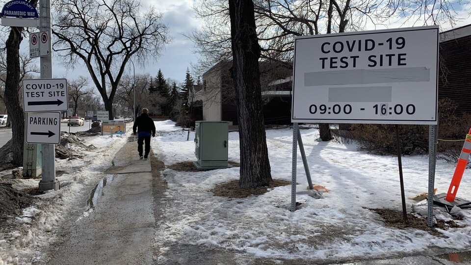 Une pancarte près du trottoir avec des informations qui indiquent que c'est un centre de dépistage de la COVID-19.