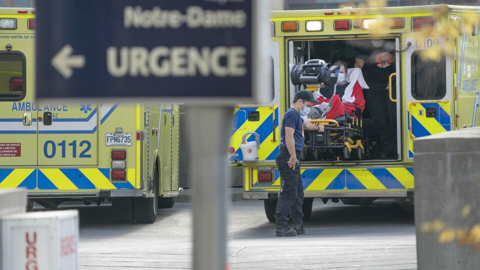 Des ambulanciers sortent un patient d'une ambulance devant une pancarte disant : Notre-Dame, urgence.