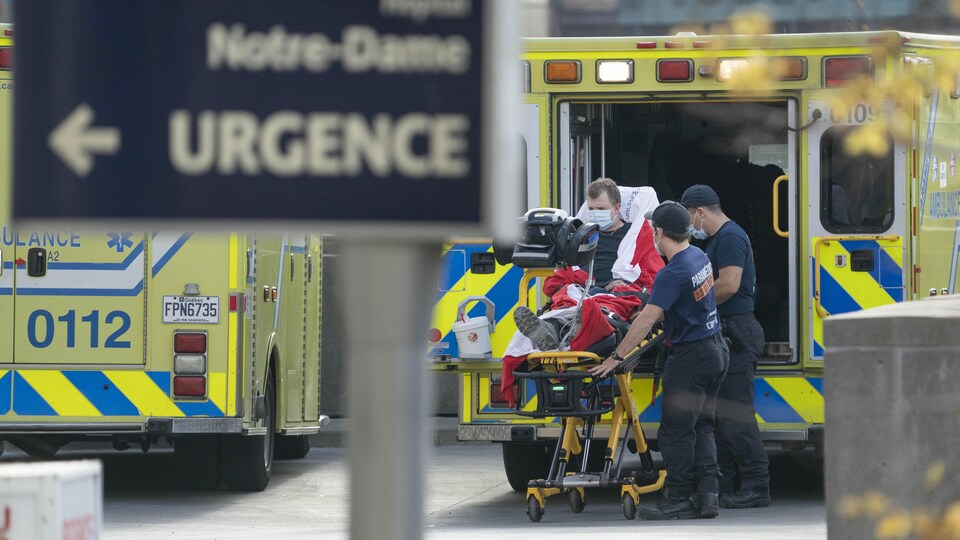 Des ambulanciers transportent un malade sur une civière.