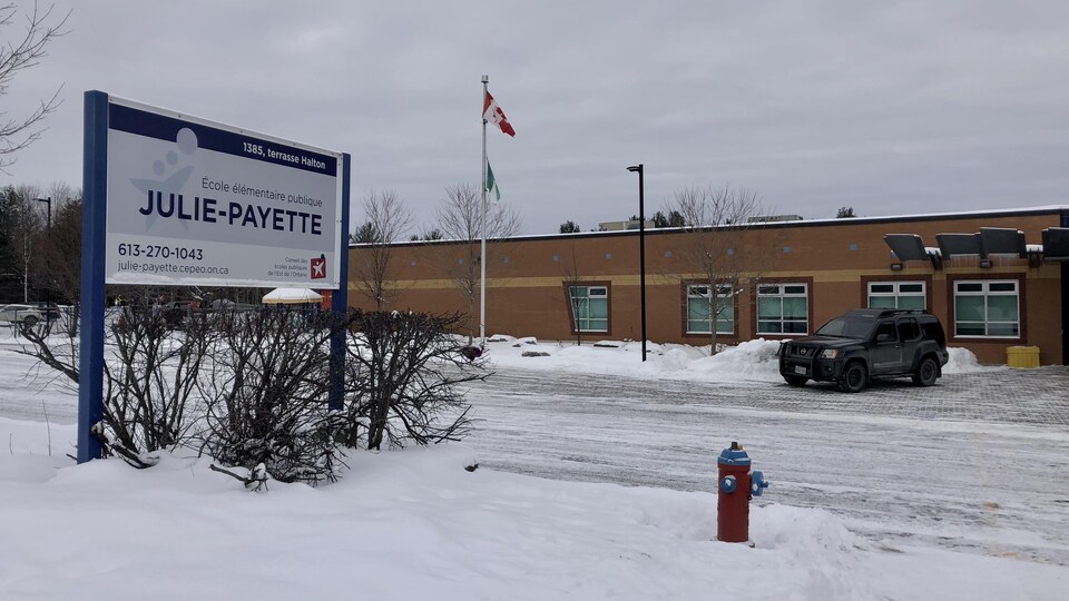 Façade de l'école entourée de neige avec l'affiche du nom de l'école primaire du Conseil des écoles publiques de l'Est de l'Ontario.