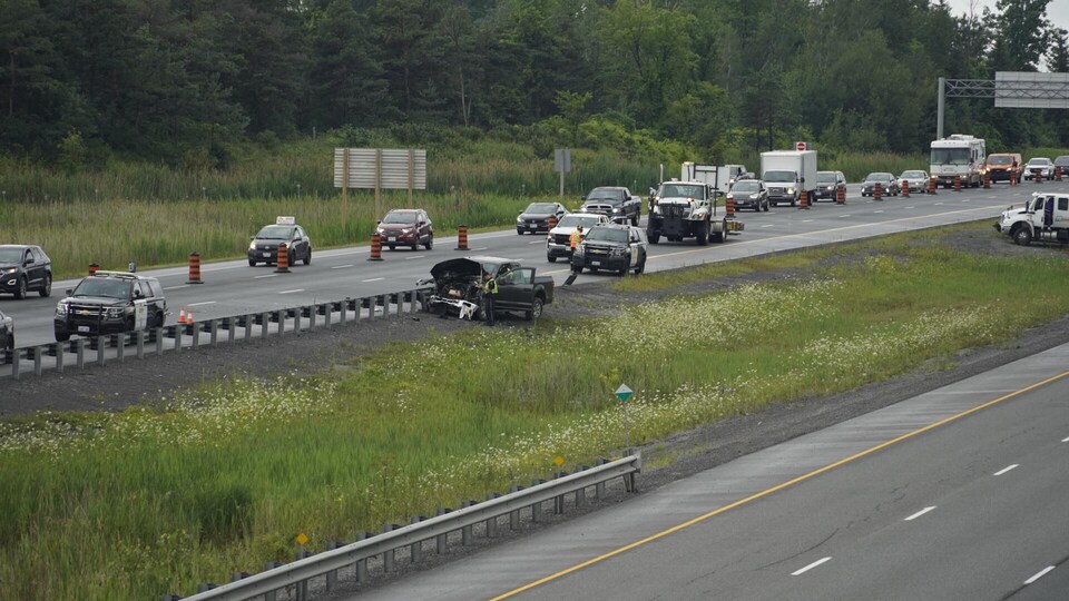Un accident sur une autoroute, avec de la circulation autour et des policiers au travail.