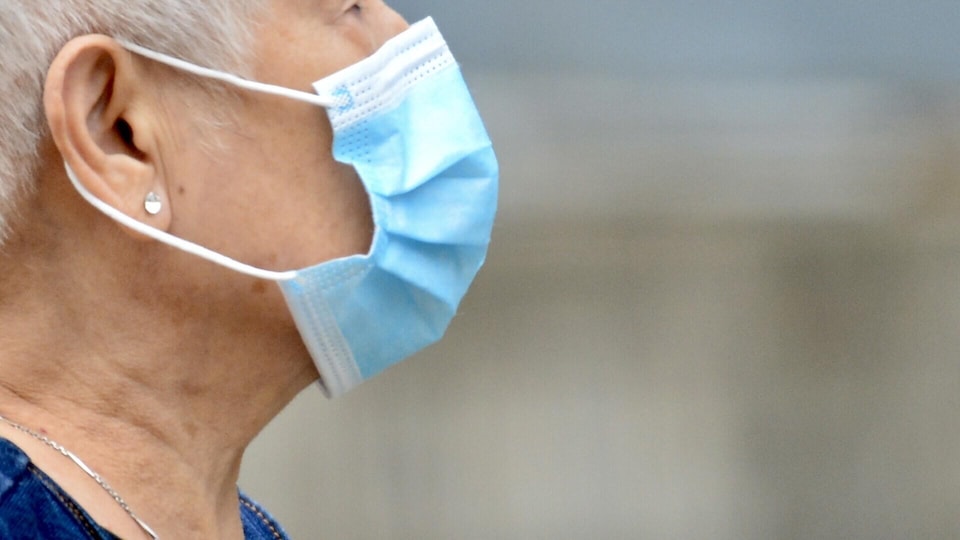 Une femme âgée portant un masque sanitaire.