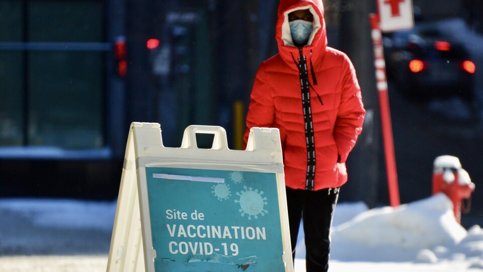 Une personne portant un masque devant un centre de vaccination.