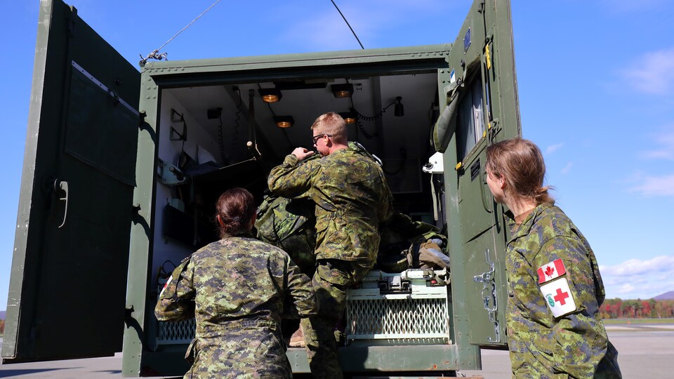 Des militaires mettent de l'équipement dans un camion.