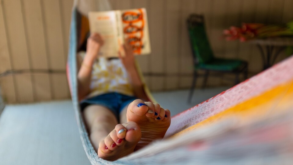 Une adolescente fait la lecture dans un hamac.
