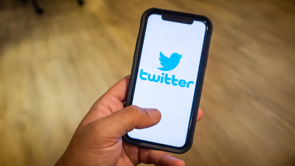 Une main tenant un téléphone avec le logo de Twitter.