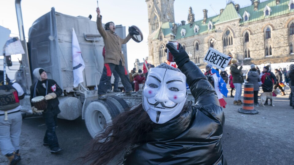 Des manifestants près d'un camion stationné devant l'édifice de l'Est du parlement à Ottawa en hiver.