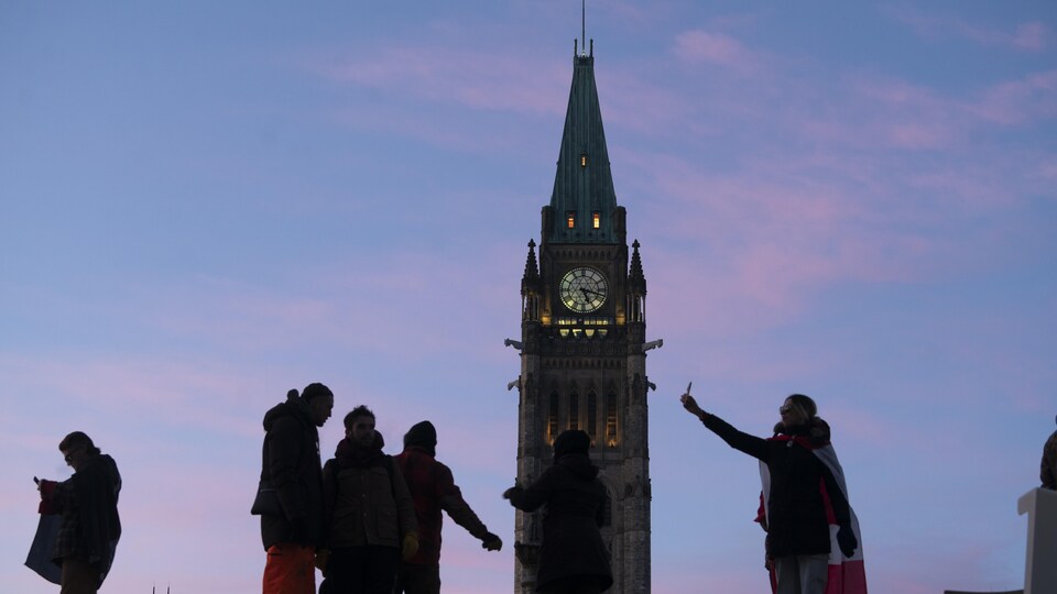 Des manifestants au crépuscule devant la Tour de la Paix à Ottawa.
